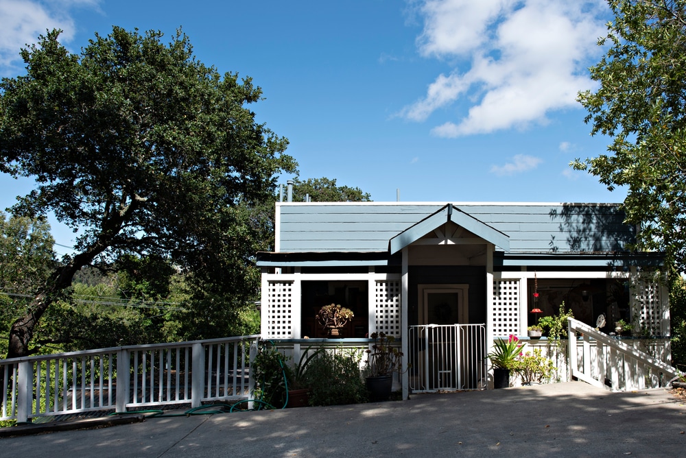 A Small Suburban Blue and White House Perched on a Hilltop Surrounded by Trees